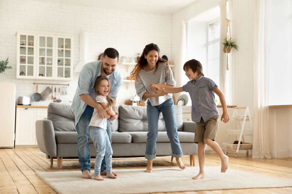 A happy family plays in the living room of their new home after working with a Madison Realtor